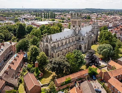 Aerial view of Selby Abbey surrounded by trees and red-roofed houses