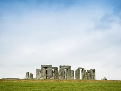 Stonehenge standing on open grassland under a wide grey sky in Wiltshire