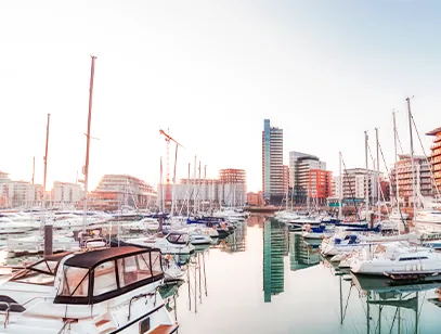 Yachts moored in a marina with waterfront apartment blocks behind in Southampton