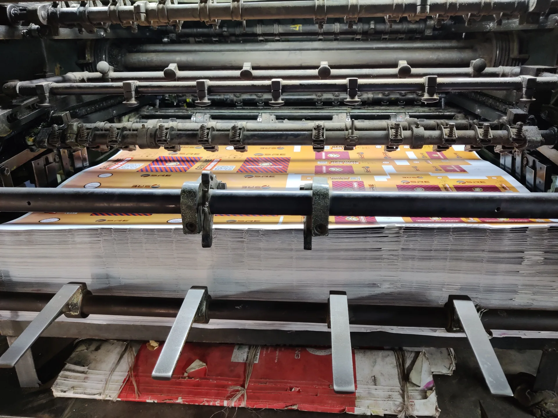Offset printing press running four-colour printed sheets