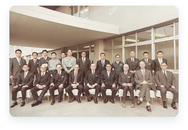 Historic group photo of early GIIGNL members in formal attire, taken in the 1970s outside a building, marking the early days of the LNG importers association.