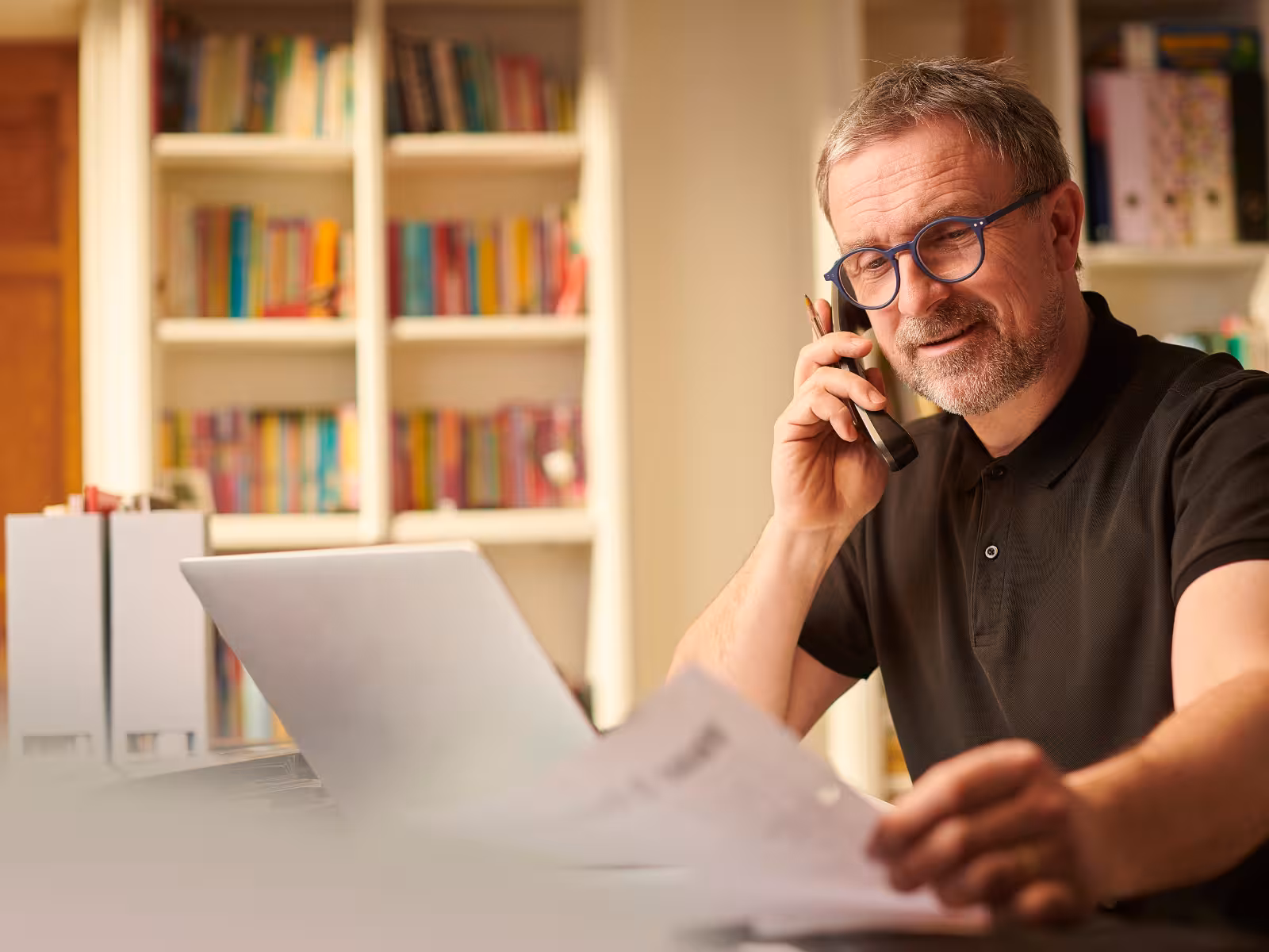 Busy business owner managing a phone call, laptop and paperwork