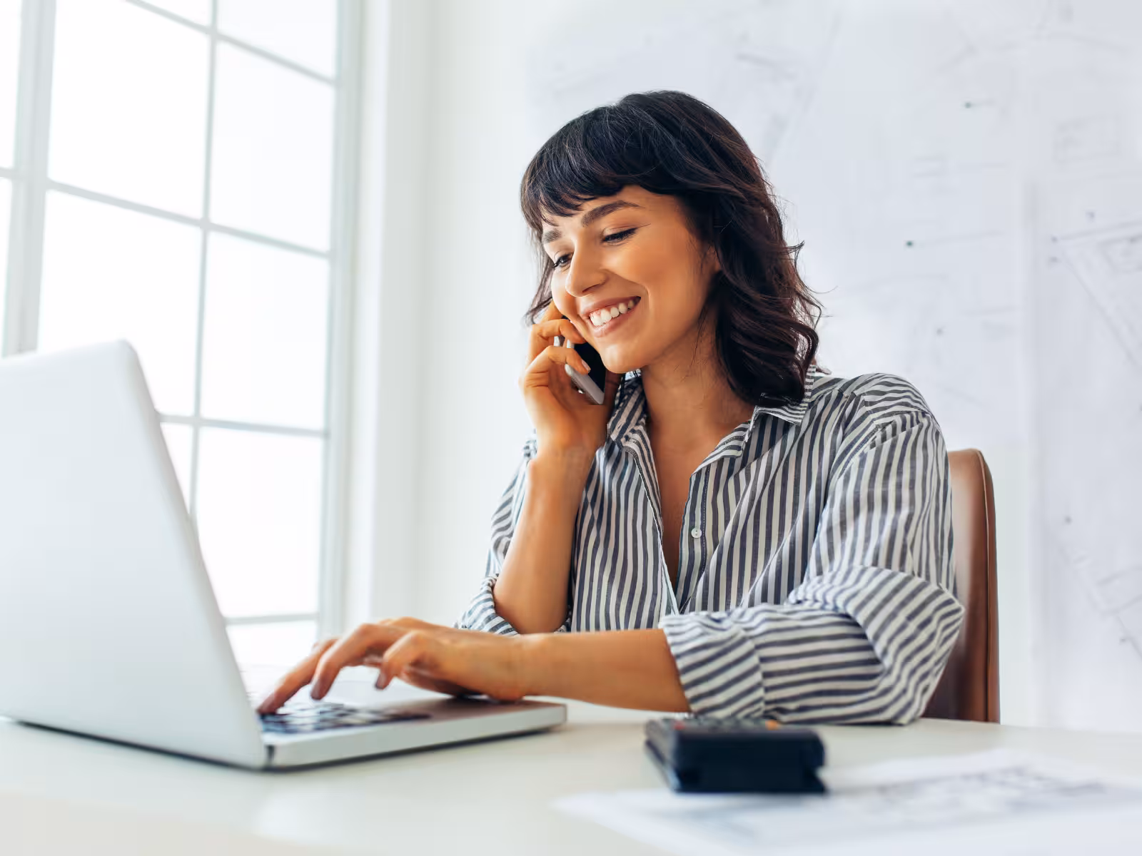 Customer service professional speaking on the phone while working on a laptop