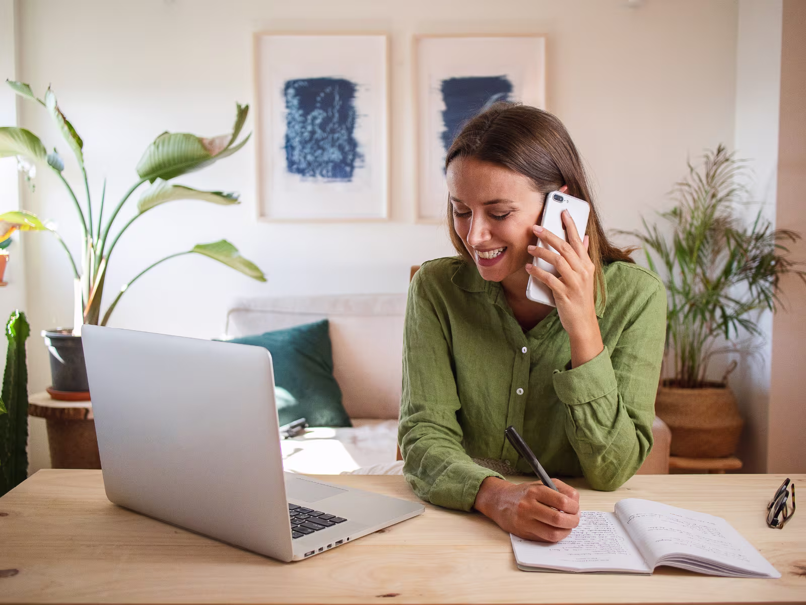 Sales professional speaking with a prospect by phone while taking notes