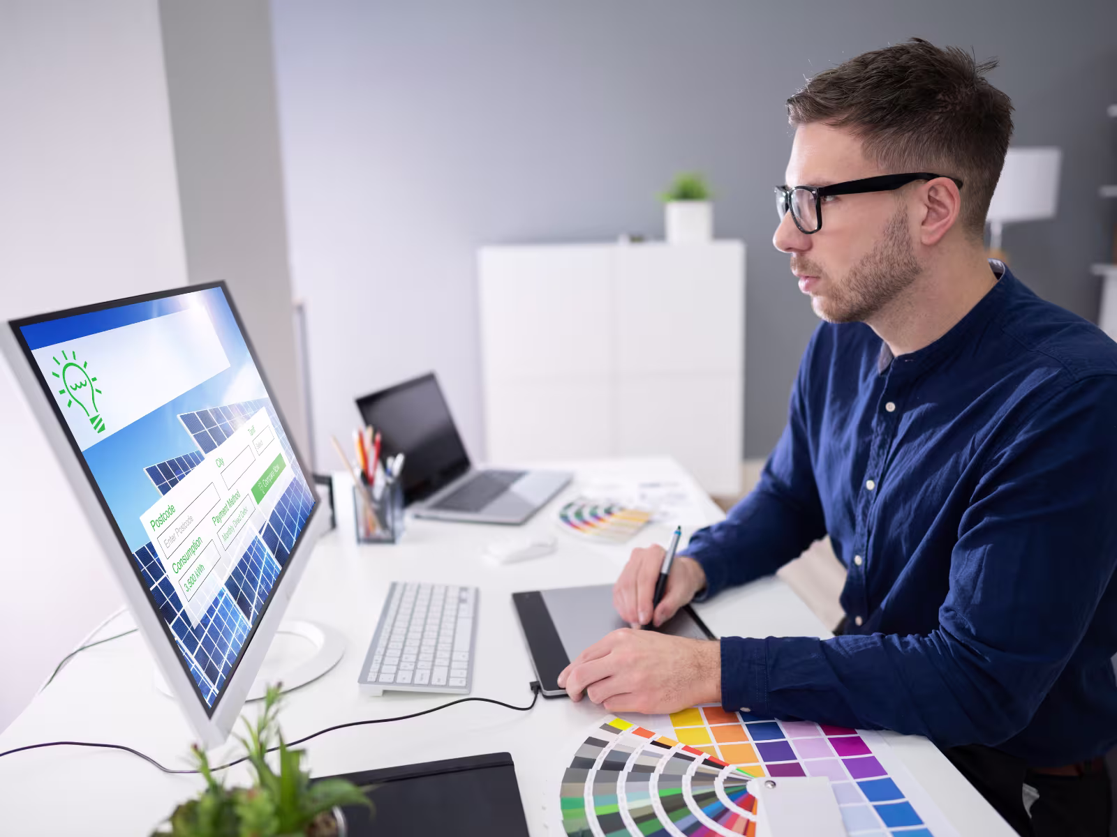 Designer working at a computer with a graphics tablet and colour swatches