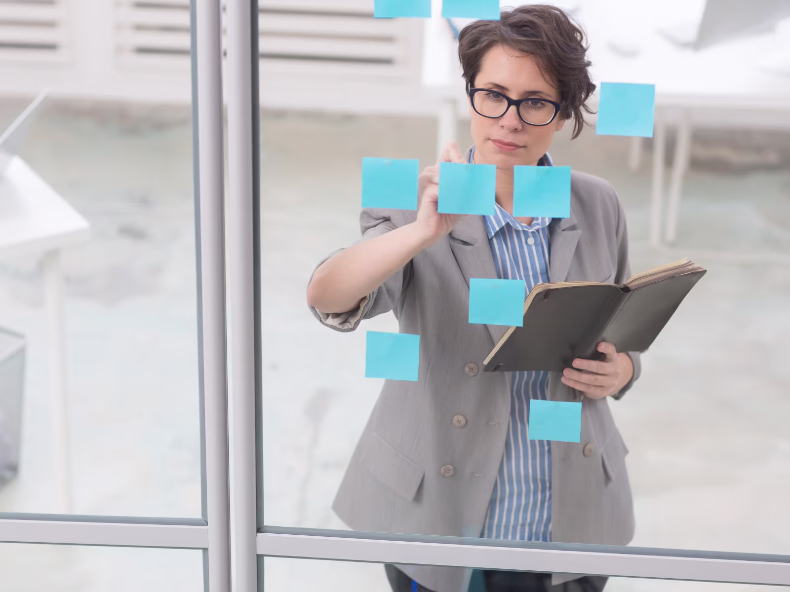 Business professional organising ideas and processes using notes on a glass wall