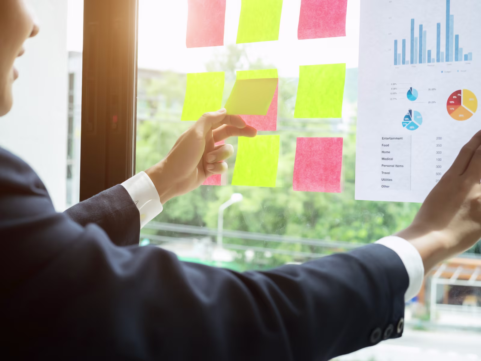 Business professional organising project tasks and data using sticky notes and charts