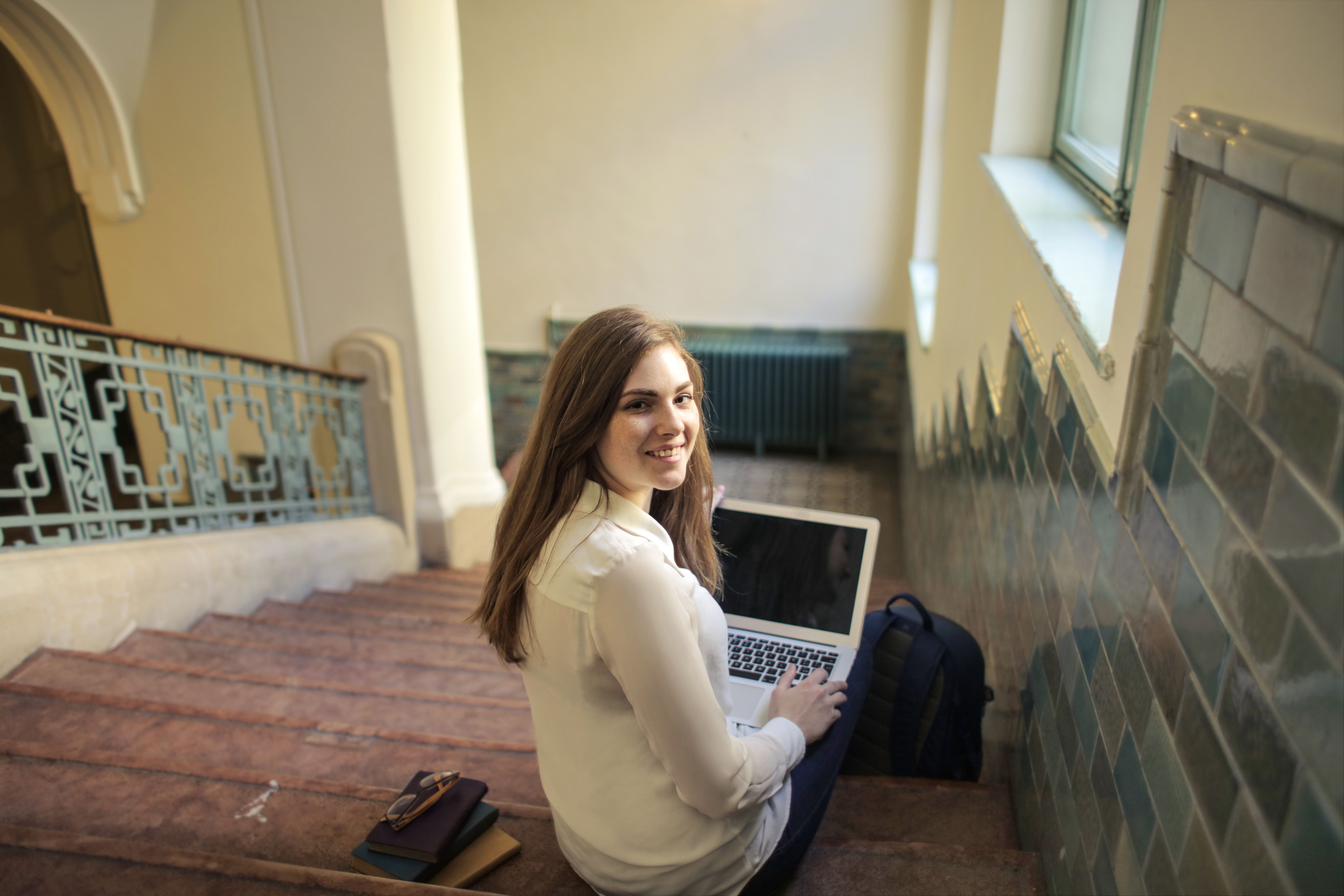 Community college student researching transcript evaluation on laptop on university campus