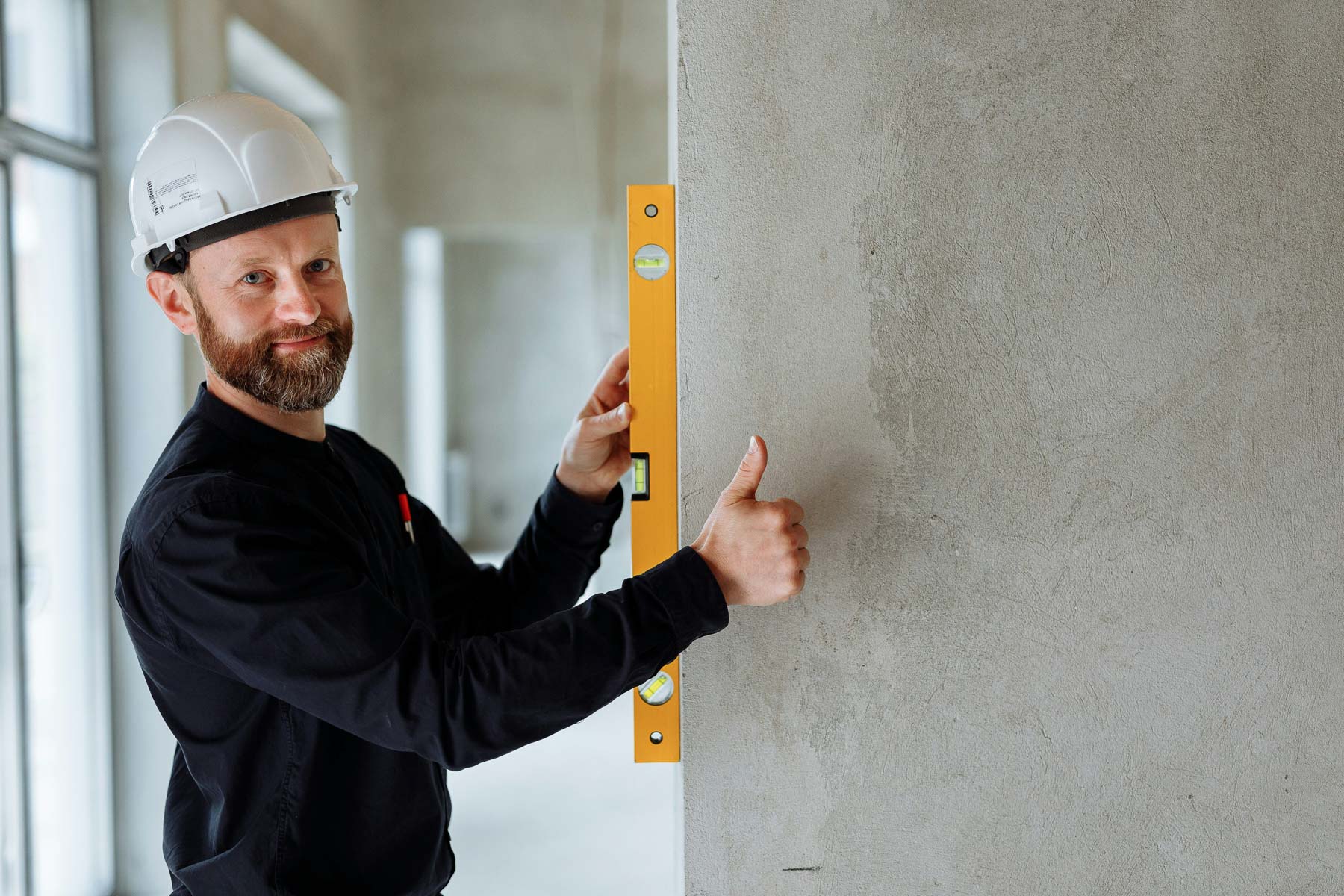 A building contractor holding a spirit level up to a wall