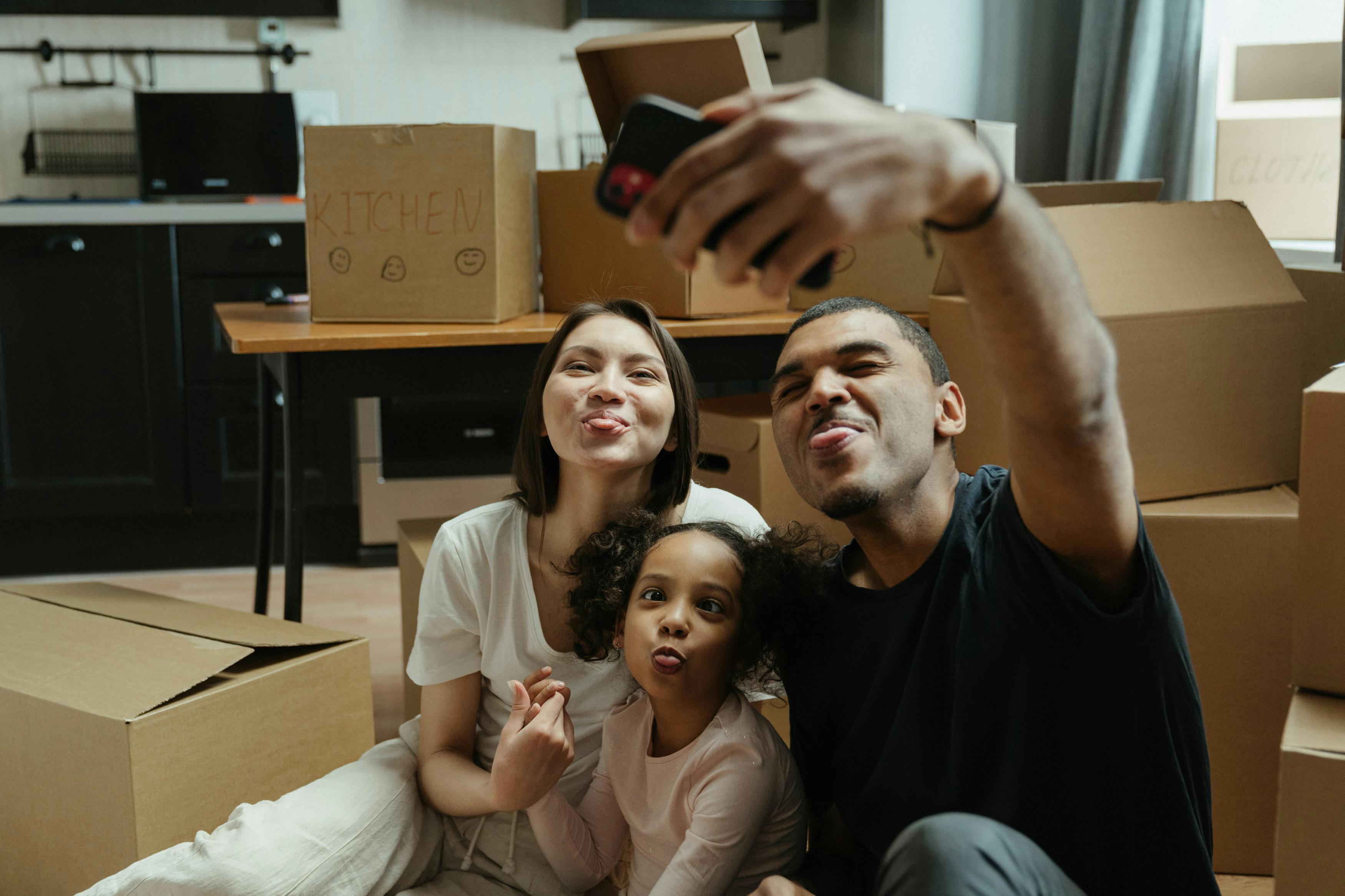 A family smiling for a picture together while unpacking in their new home