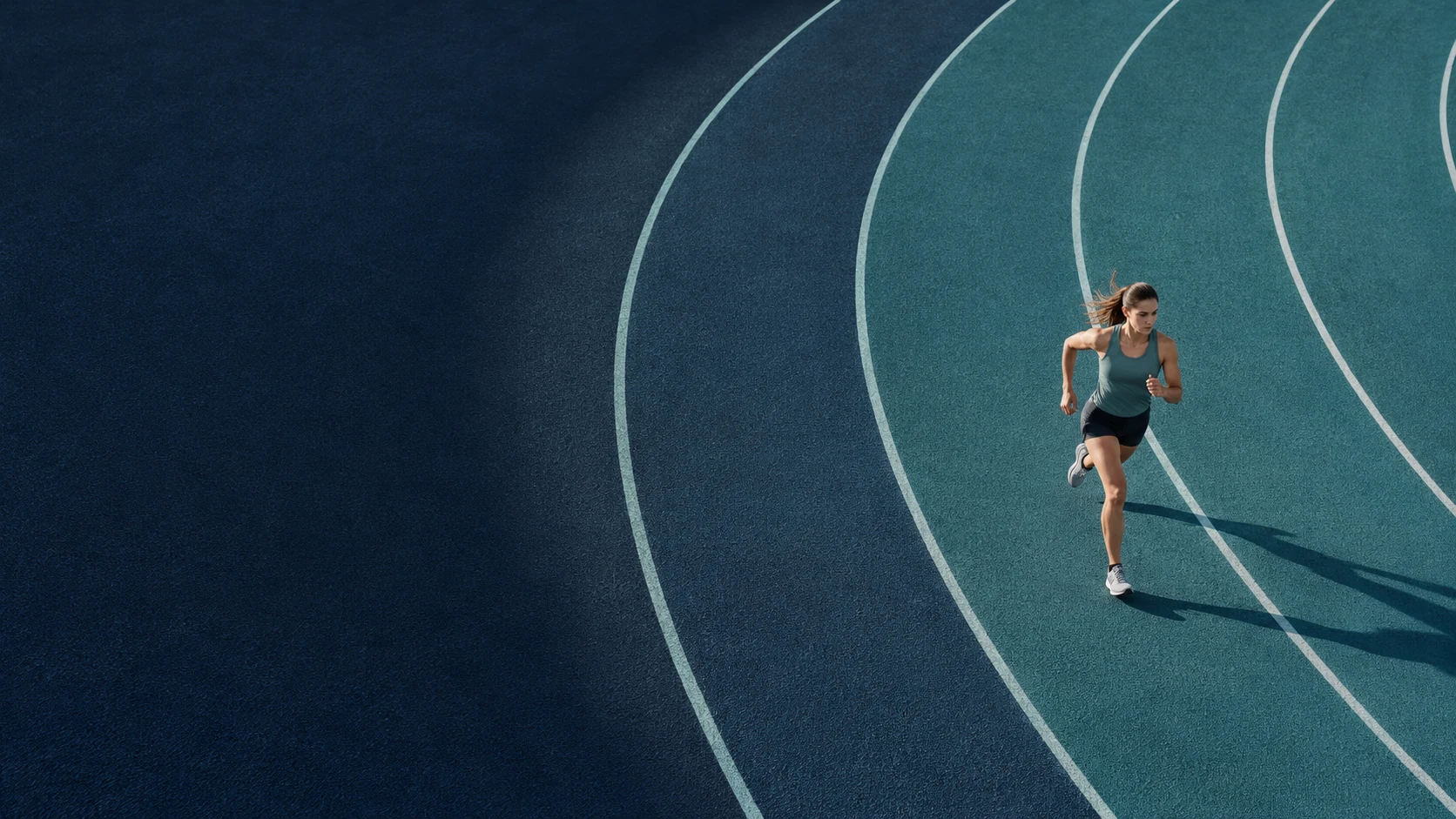 An athlete running along the curved lanes of a deep teal track.