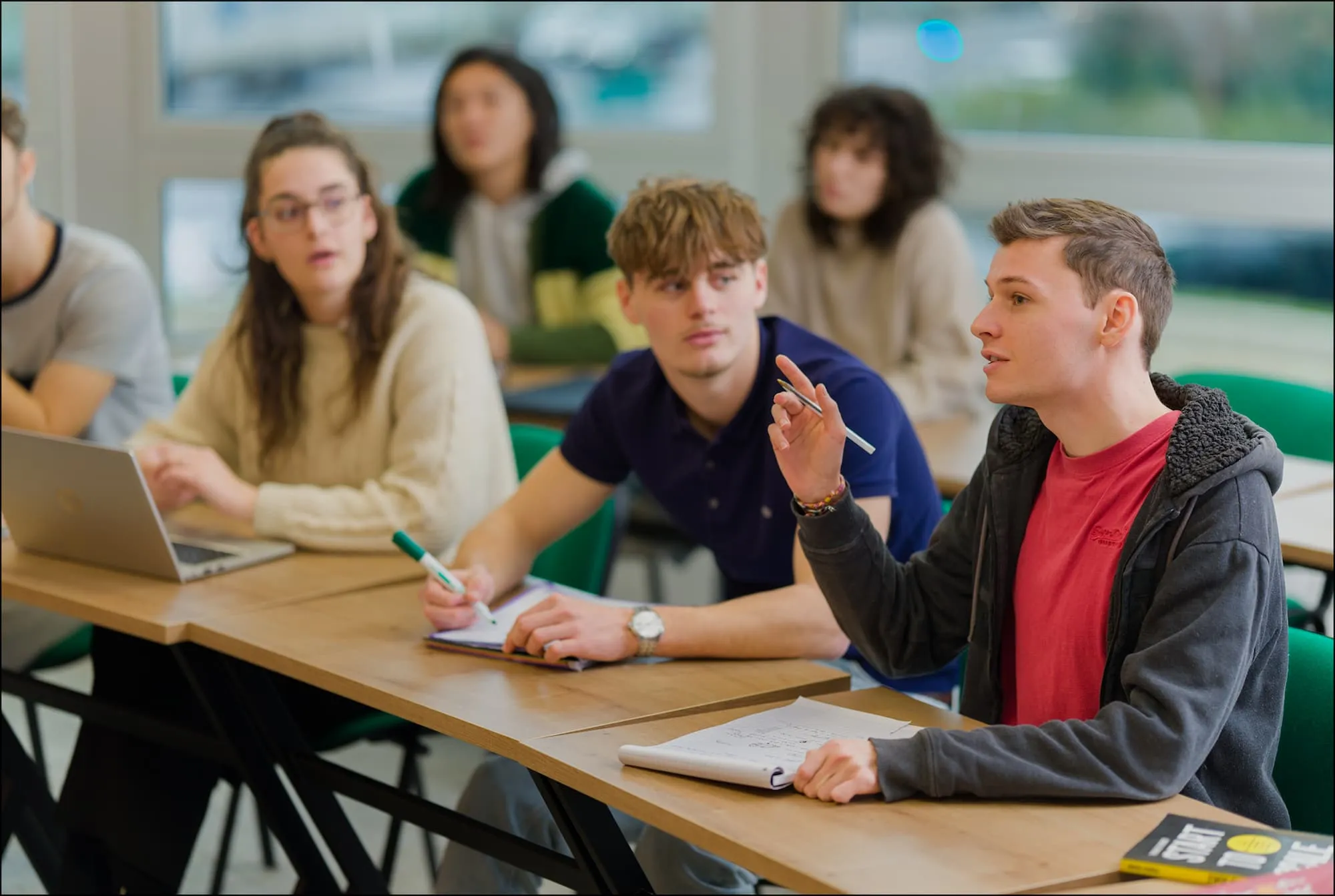 Une main atteignant une étagère de bibliothèque pour prendre un livre de finance intitulé "PIERRE VERNIMMEN FINANCE D'ENTREPRISE". À côté se trouvent d'autres ouvrages professionnels dont des codes fiscaux et sociaux avec l'indication "24" et des livres "MÉMENTO PRATIQUE". Cette image illustre l'accès aux ressources pédagogiques spécialisées en finance, comptabilité et droit disponibles pour les étudiants de l'Institut d'Économie Durable.
