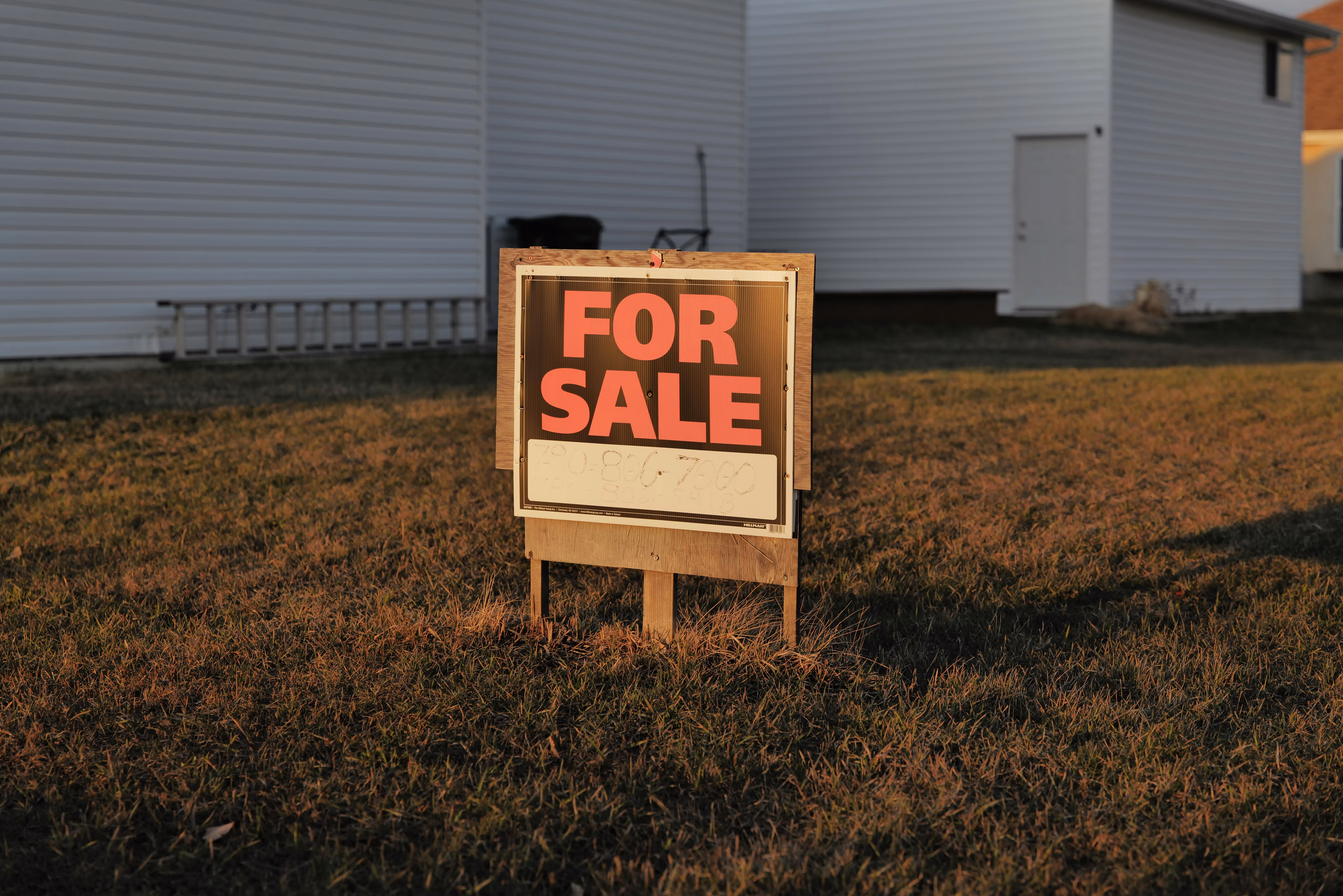 Immobilie als Kapitalanlage zu verkaufen – For-Sale-Schild vor Haus bei Sonnenuntergang
