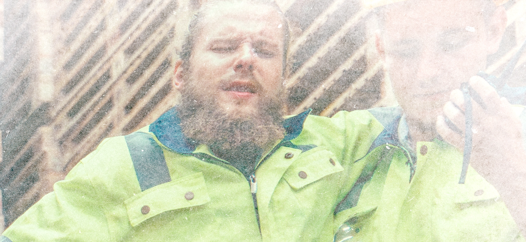 Mann in Arbeitskleidung hält sich beim Heben eines Kartons im Lager den schmerzenden Rücken