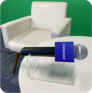 Cadeira branca moderna com microfone azul na frente, ideal para gravações e entrevistas em estúdios, com fundo verde.