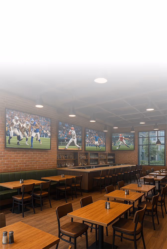 Intérieur de bar sportif comprenant des tables en bois, des chaises, des cabines vertes et des téléviseurs muraux diffusant des événements sportifs en direct.