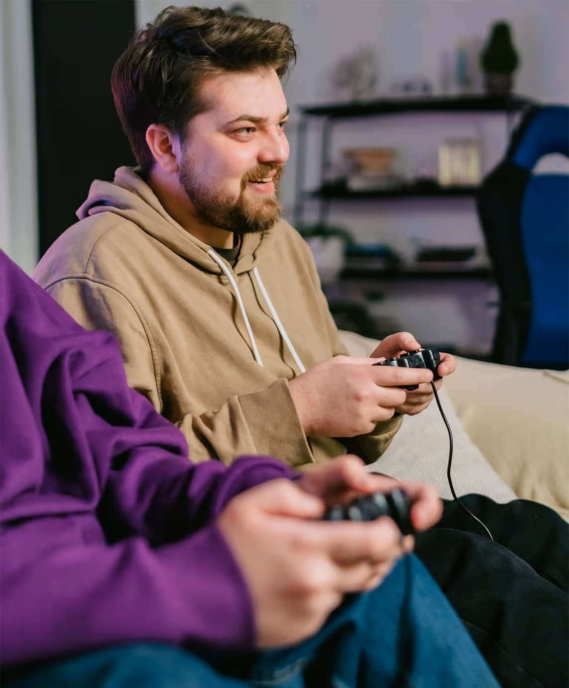 Deux personnes assises sur un canapé, concentrées sur le jeu avec des manettes en main, profitant d'une session de jeu ensemble.