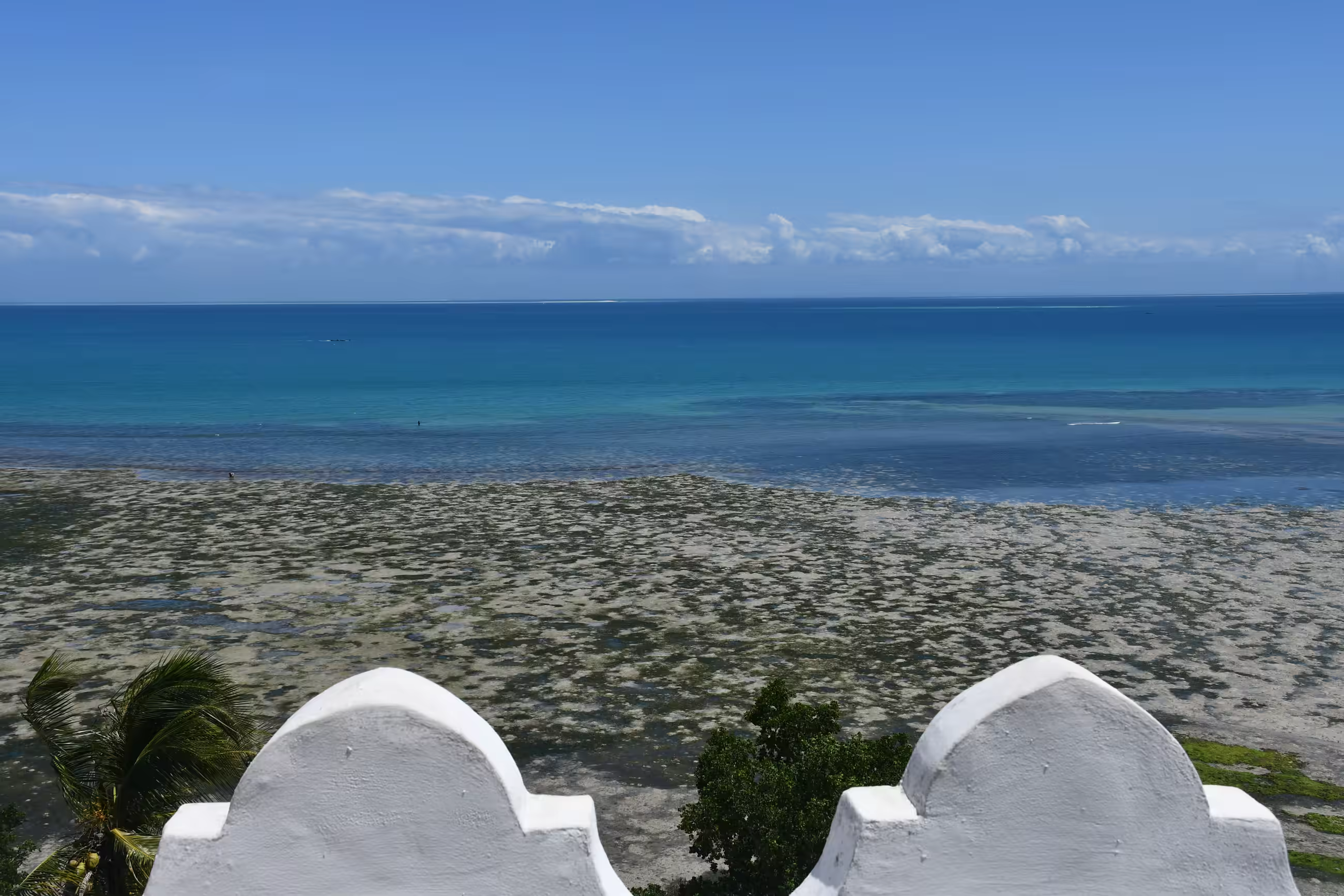 View over the exposed reef flat at low tide from a whitewashed terrace, looking out to the open Indian Ocean