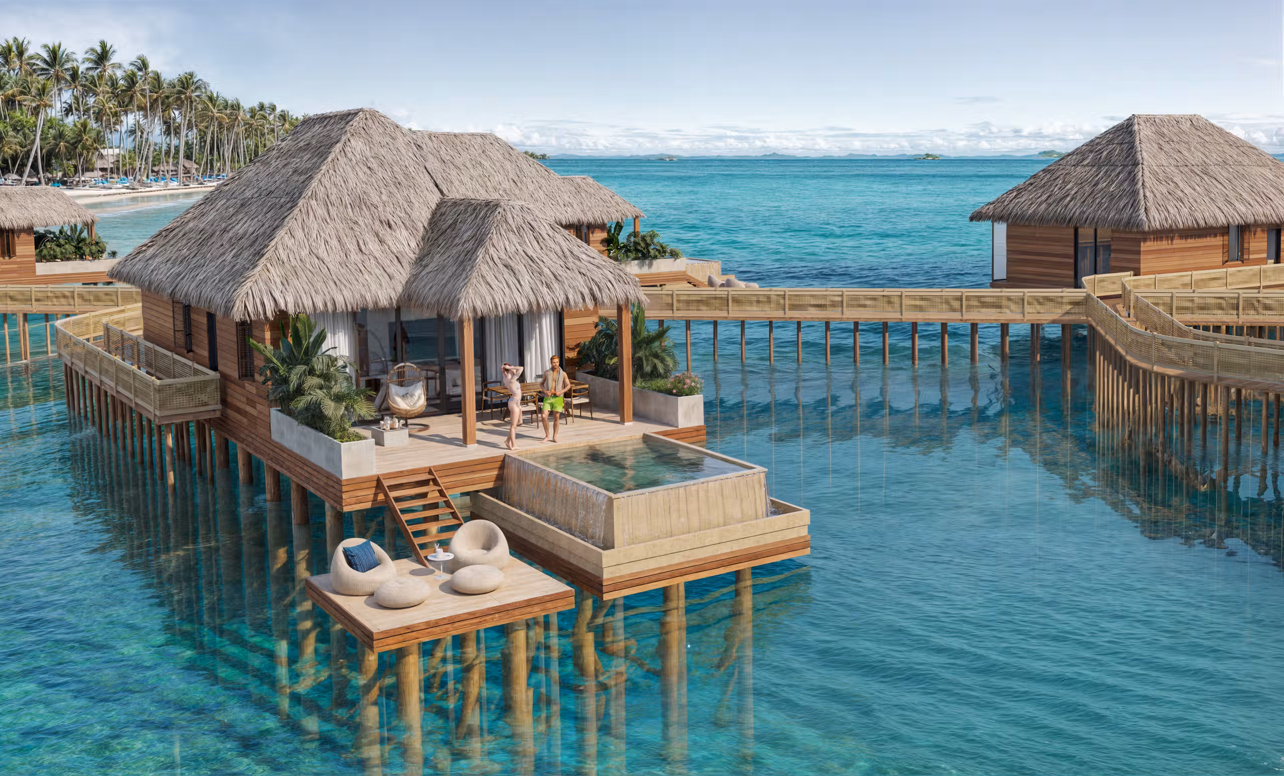 Two people stand on the deck of an overwater bungalow with a private pool and ocean view.