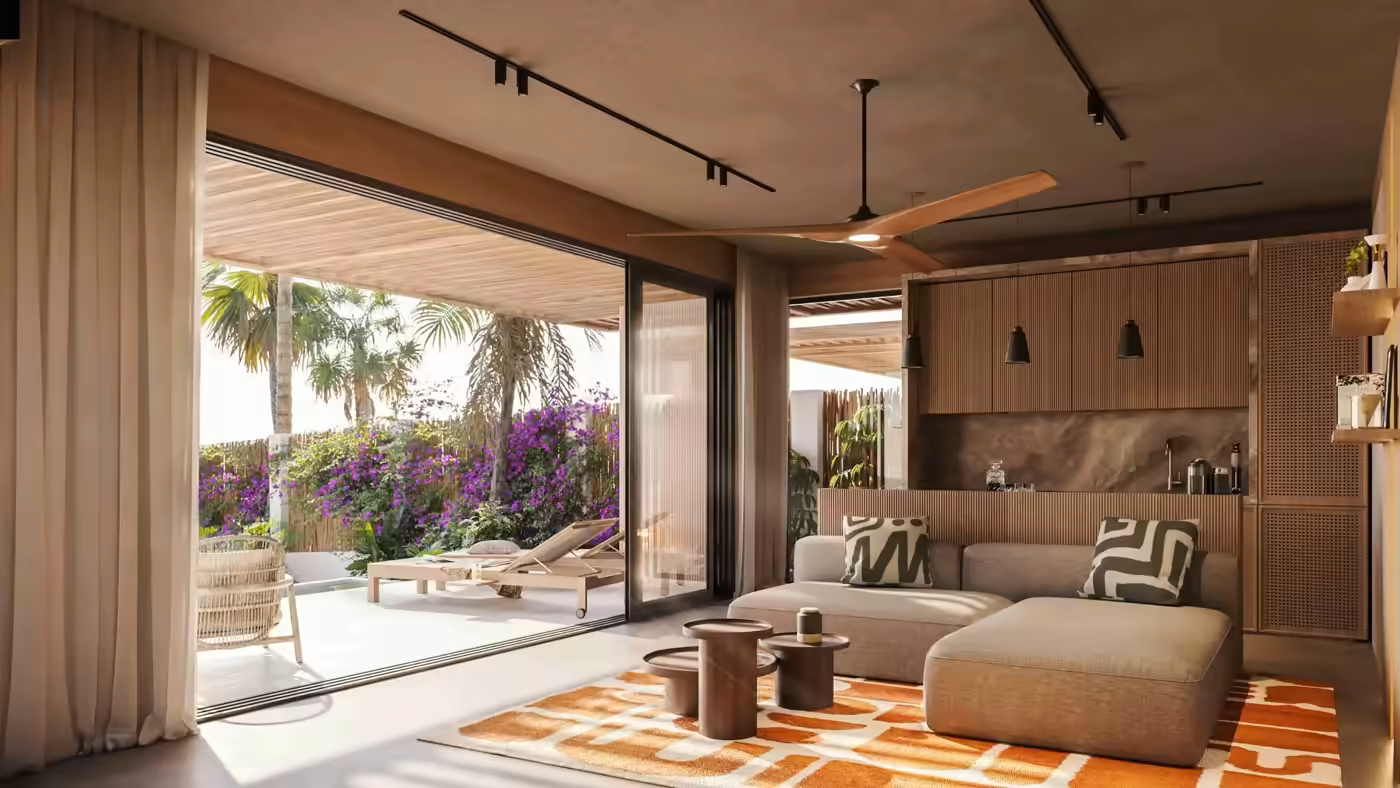 Modern living room with gray sectional sofa, patterned pillows, orange rug, and open patio with lounge chairs.