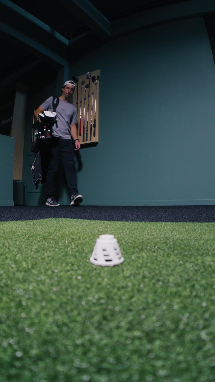 A golfer in front of the teal panelled walls with his bag of clubs