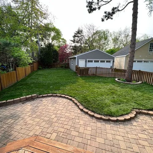 A freshly cut green lawn with a patio made of brick