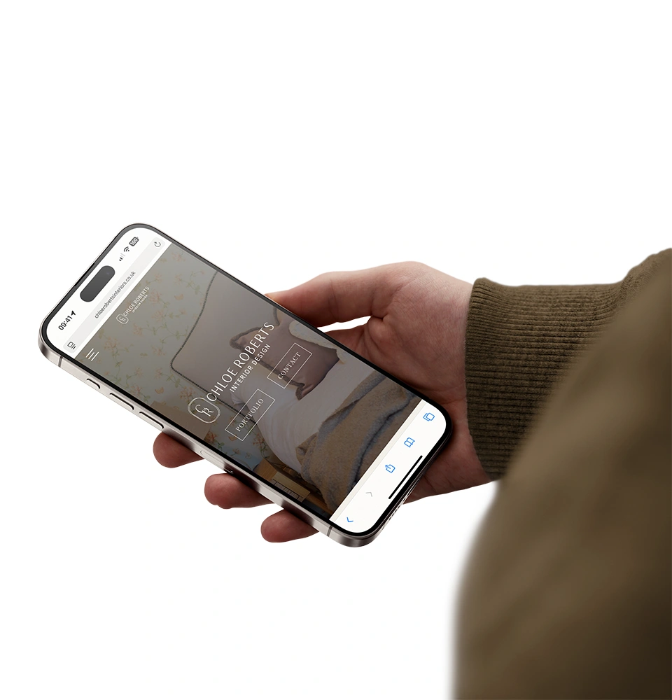 Person holding a smartphone displaying Chloe Roberts interior design website with options for portfolio and contact.