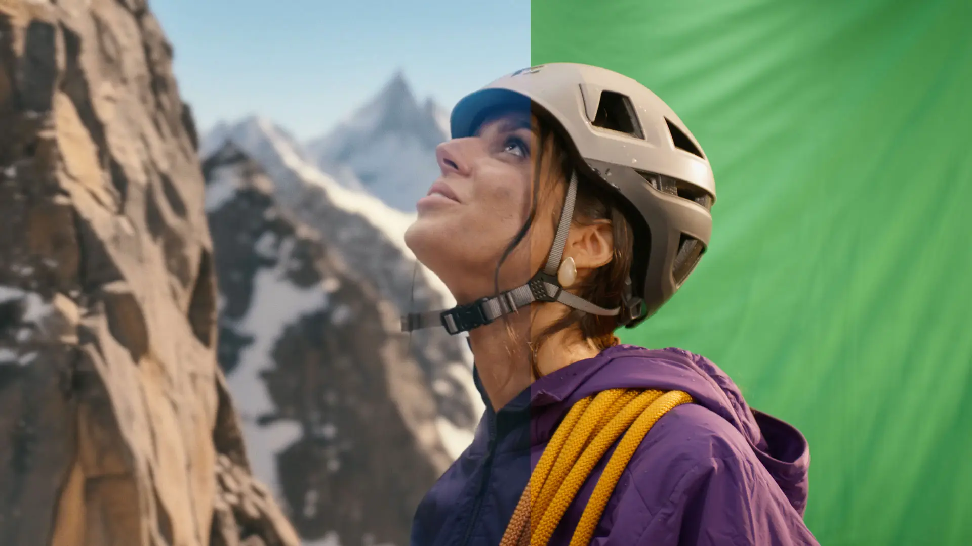 Eine junge Frau in Bergsteiger-Ausrüstung, bestehend aus einem hellgrauen Kletterhelm und einer violetten Jacke, blickt aufmerksam nach oben links. Über ihrer Schulter liegt ein gelbes Kletterseil. Das Bild ist zweigeteilt: Links sieht man eine verschwommene, felsige Bergwand und einen Hintergrund mit schneebedeckten Gipfeln; rechts ist der Hintergrund ein Green Screen