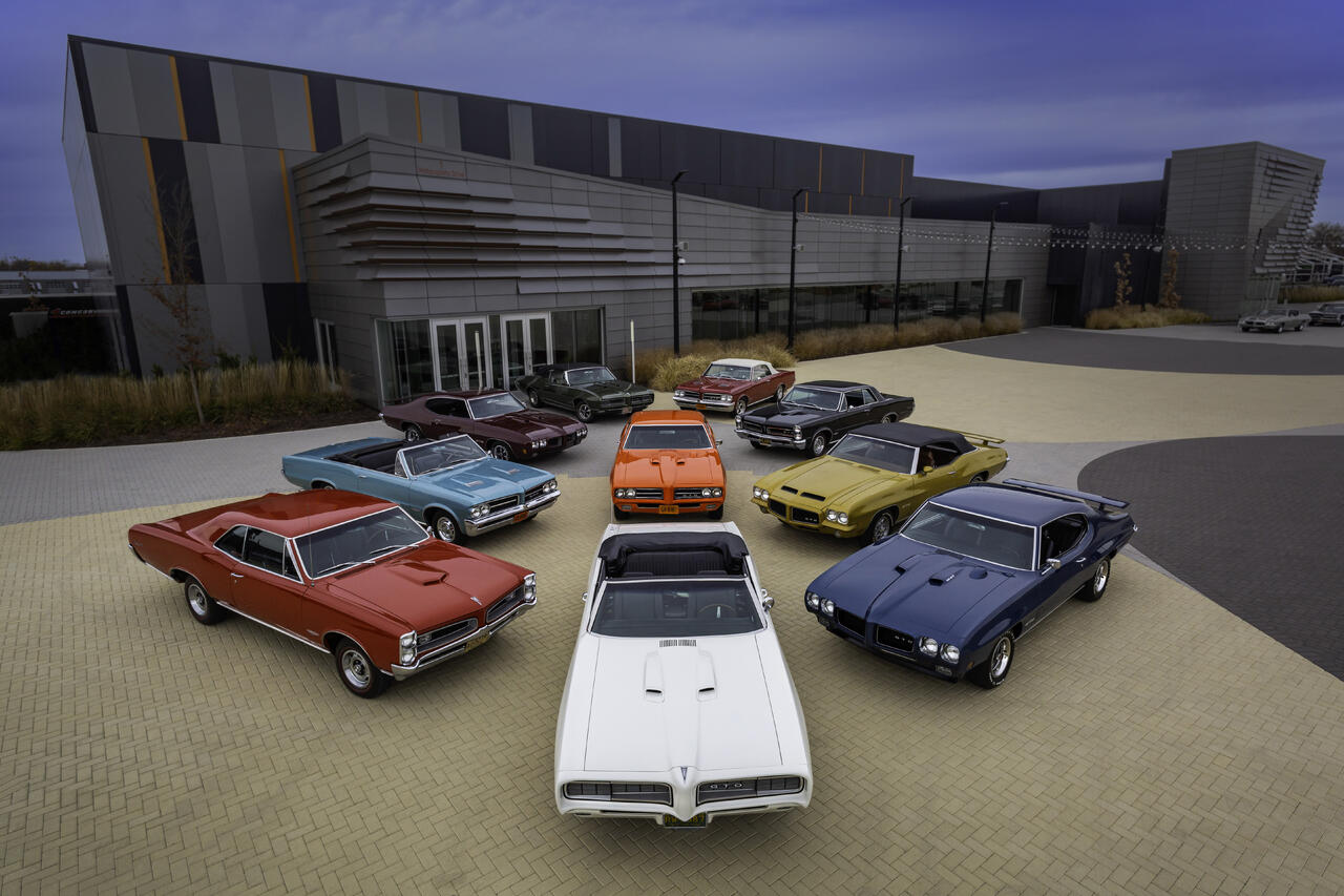 10 Pontiac GTO cars positioned for a photo on a brick plaza.