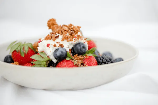 A bowl of Greek yoghurt sprinkled with berries as a healthy choice for menopause diet 