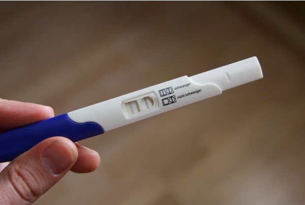 Close-up of a pregnancy test being held, showing the test result window, demonstrating how to read a pregnancy test