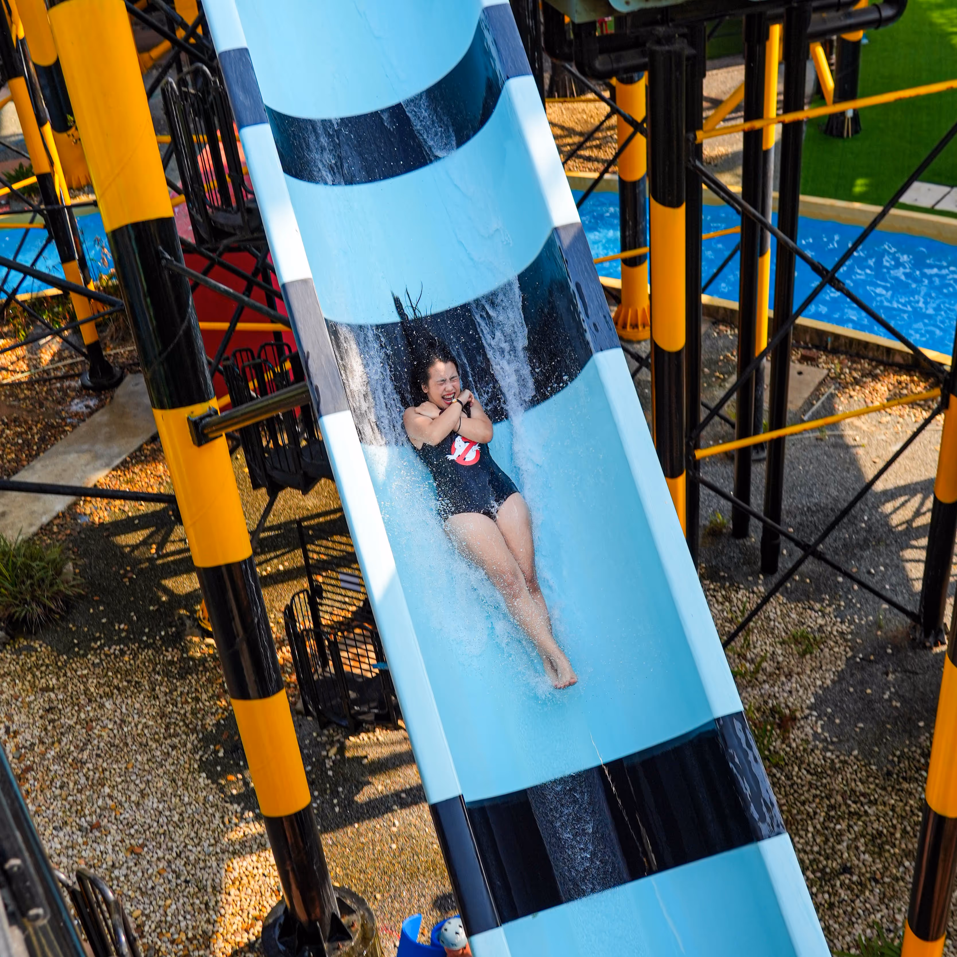 Close-up view of a red launch capsule water slide at Columbia Pictures Aquaverse, surrounded by a giant zombie hand prop, part of the Zombieland-themed attraction.