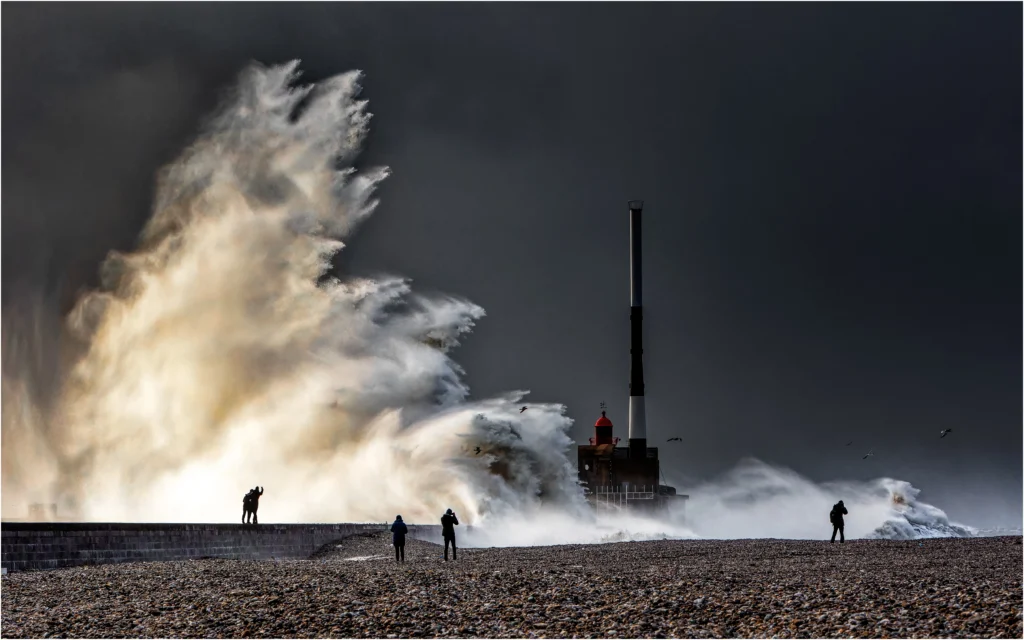 Une vague s'écrase sur le phrase du port du havre, classé 4ème au concours photo WinSPOT by Data Concept 2023-2024