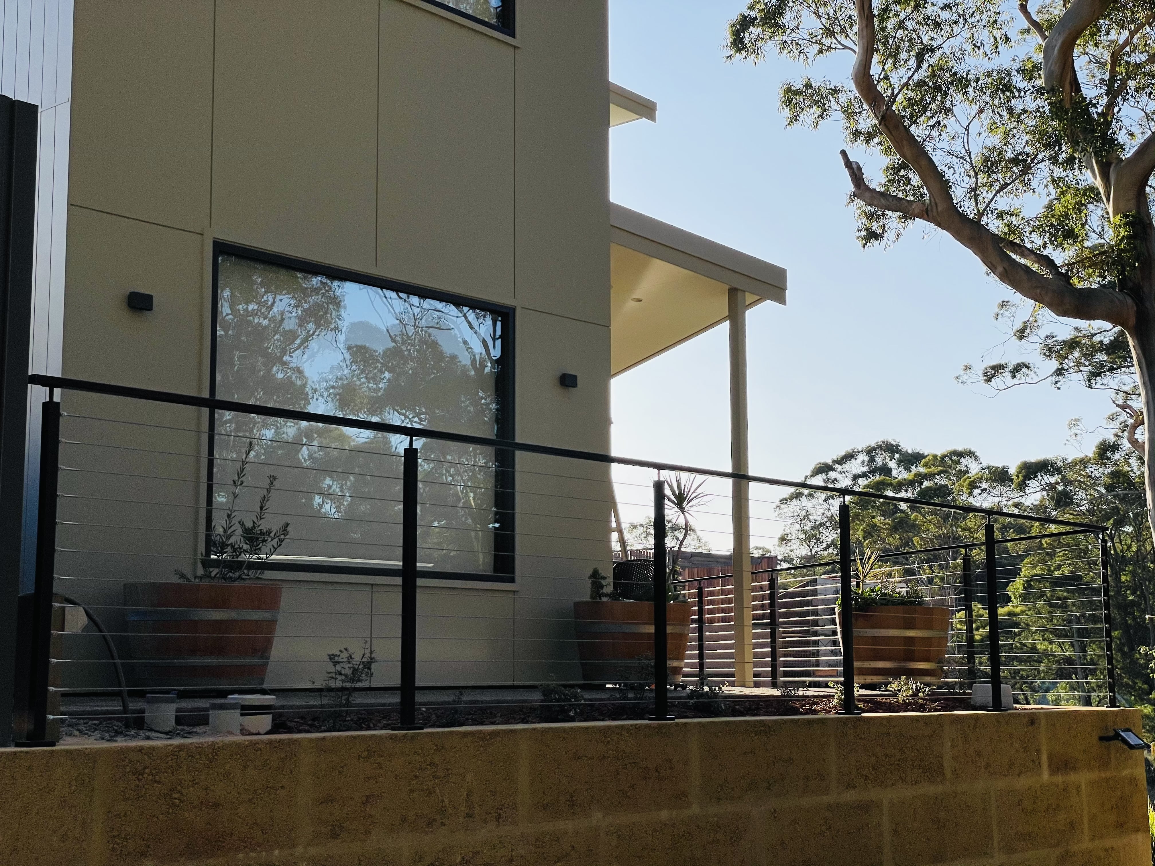 Black wire balustrade along a rendered home's raised limestone wall