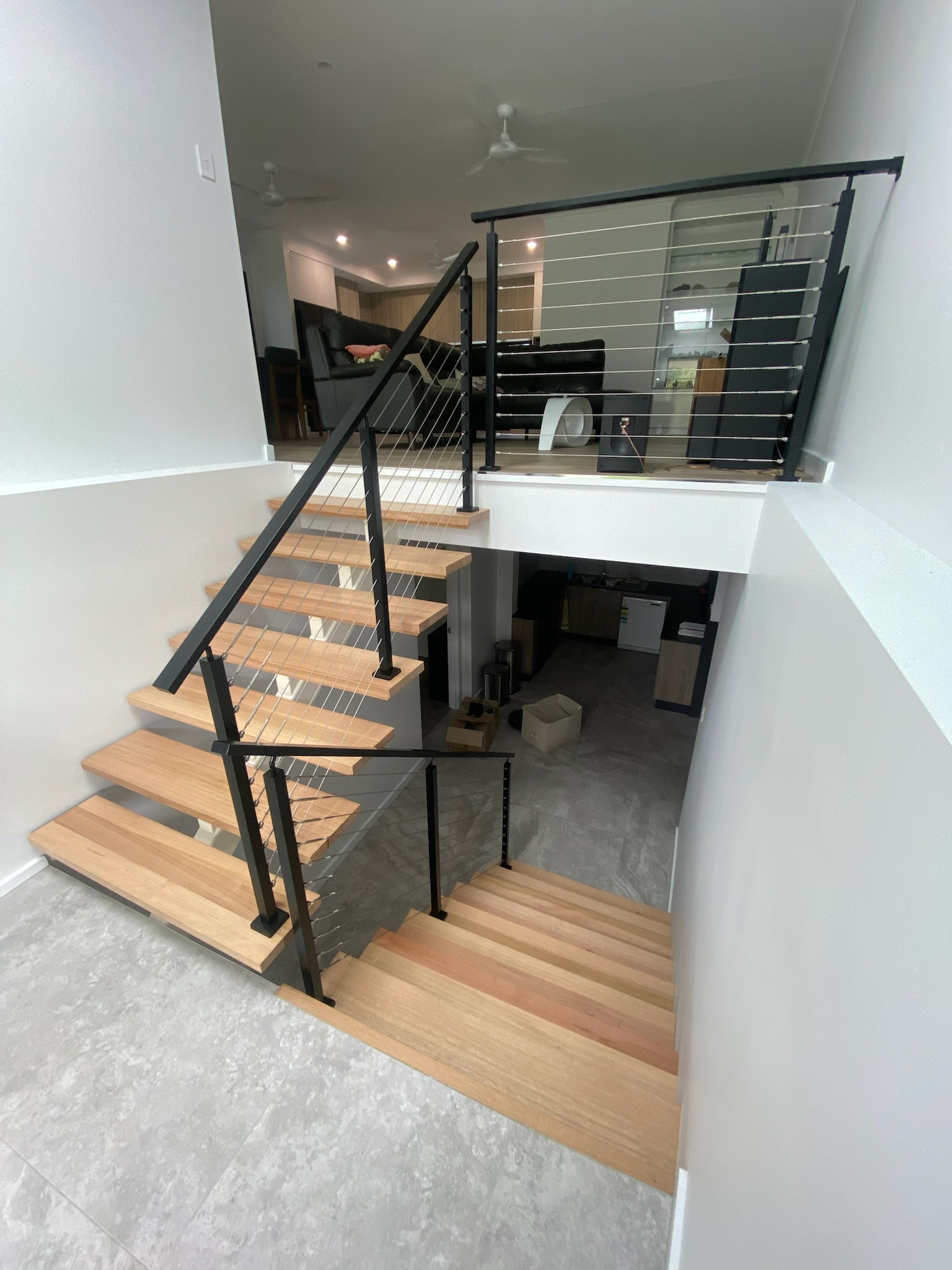 Interior timber-tread staircase with black posts and stainless wire balustrade