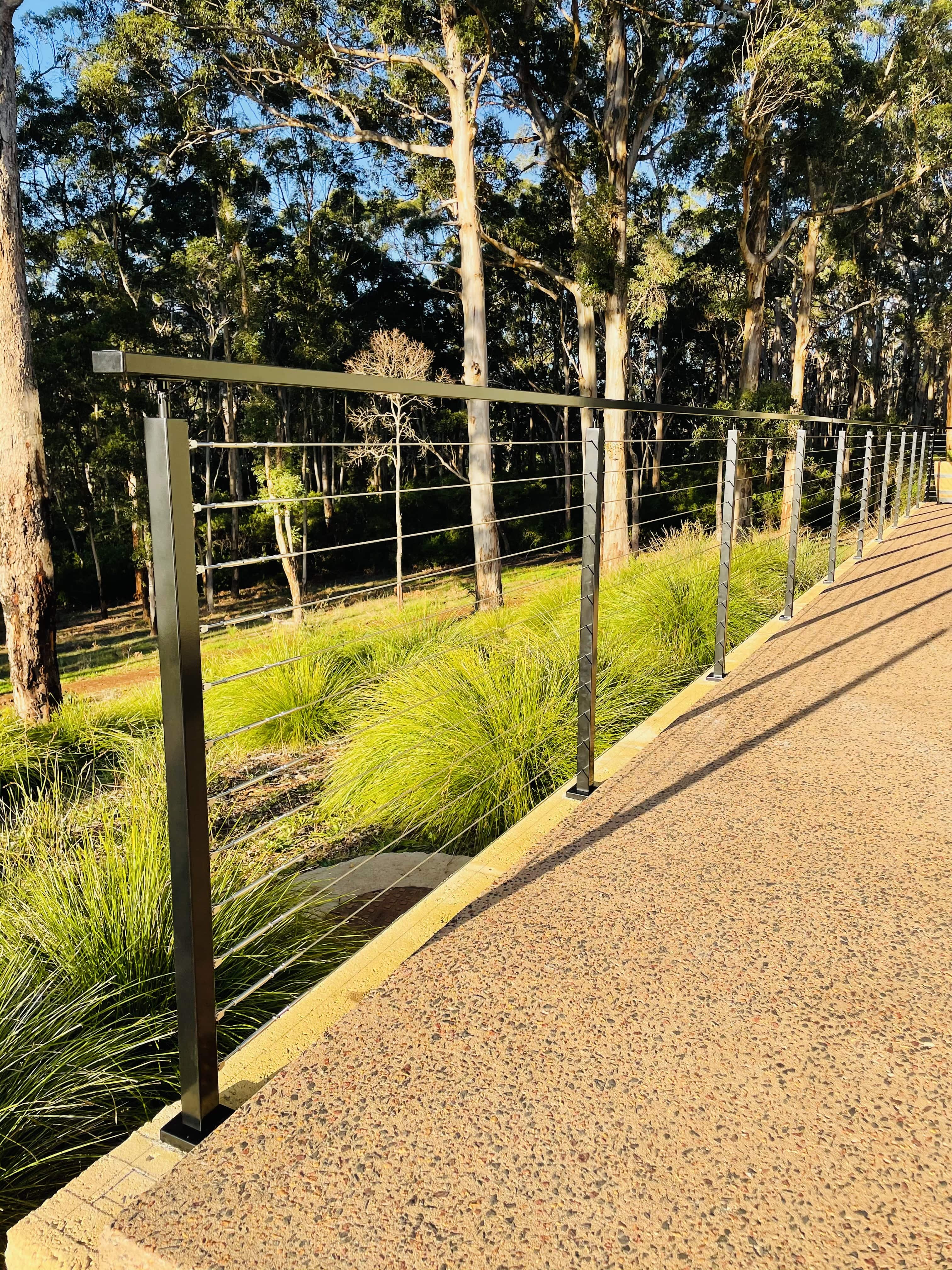 Stainless steel wire balustrade lining a driveway through WA bushland