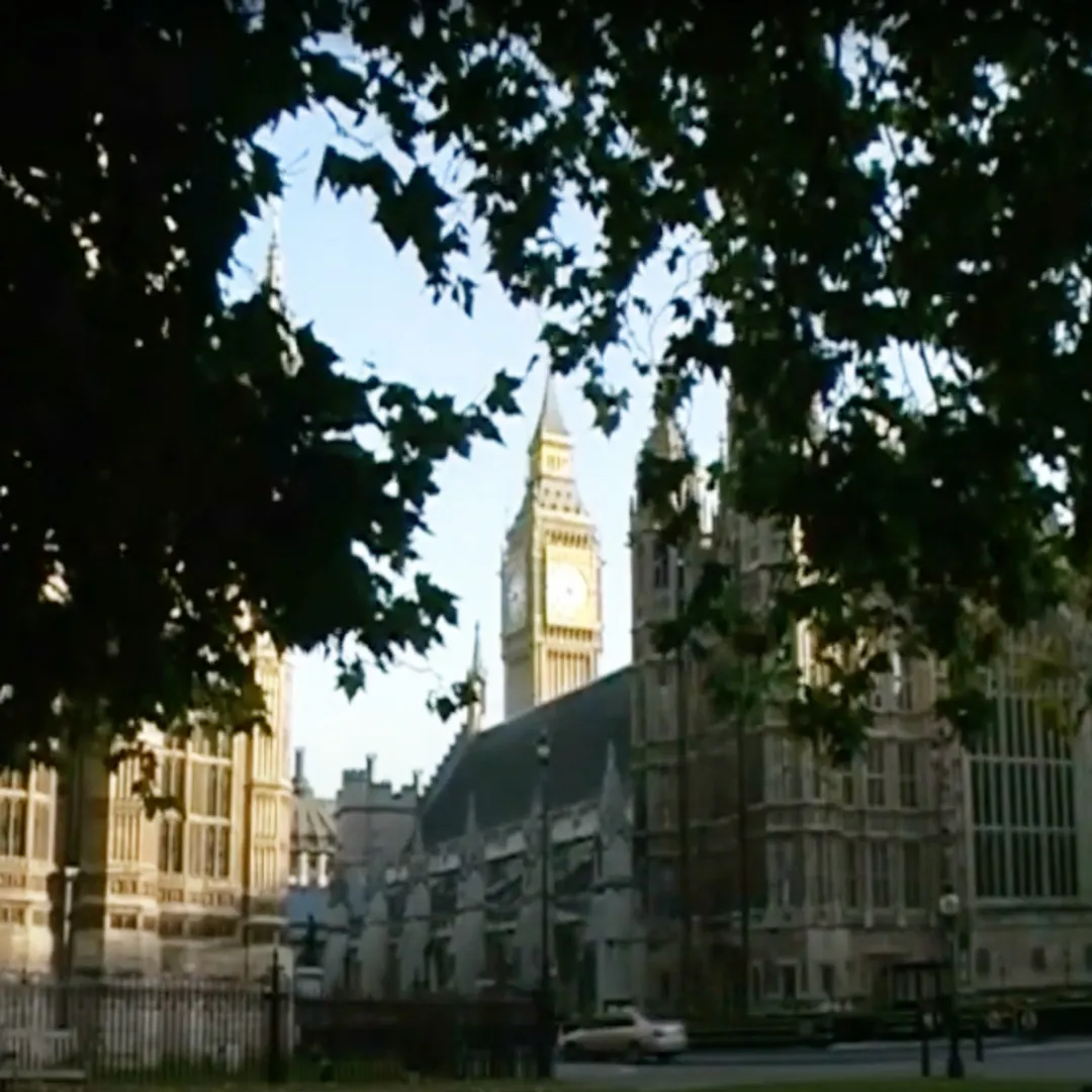 An old picture of Parliament and Big Ben framed by trees.
