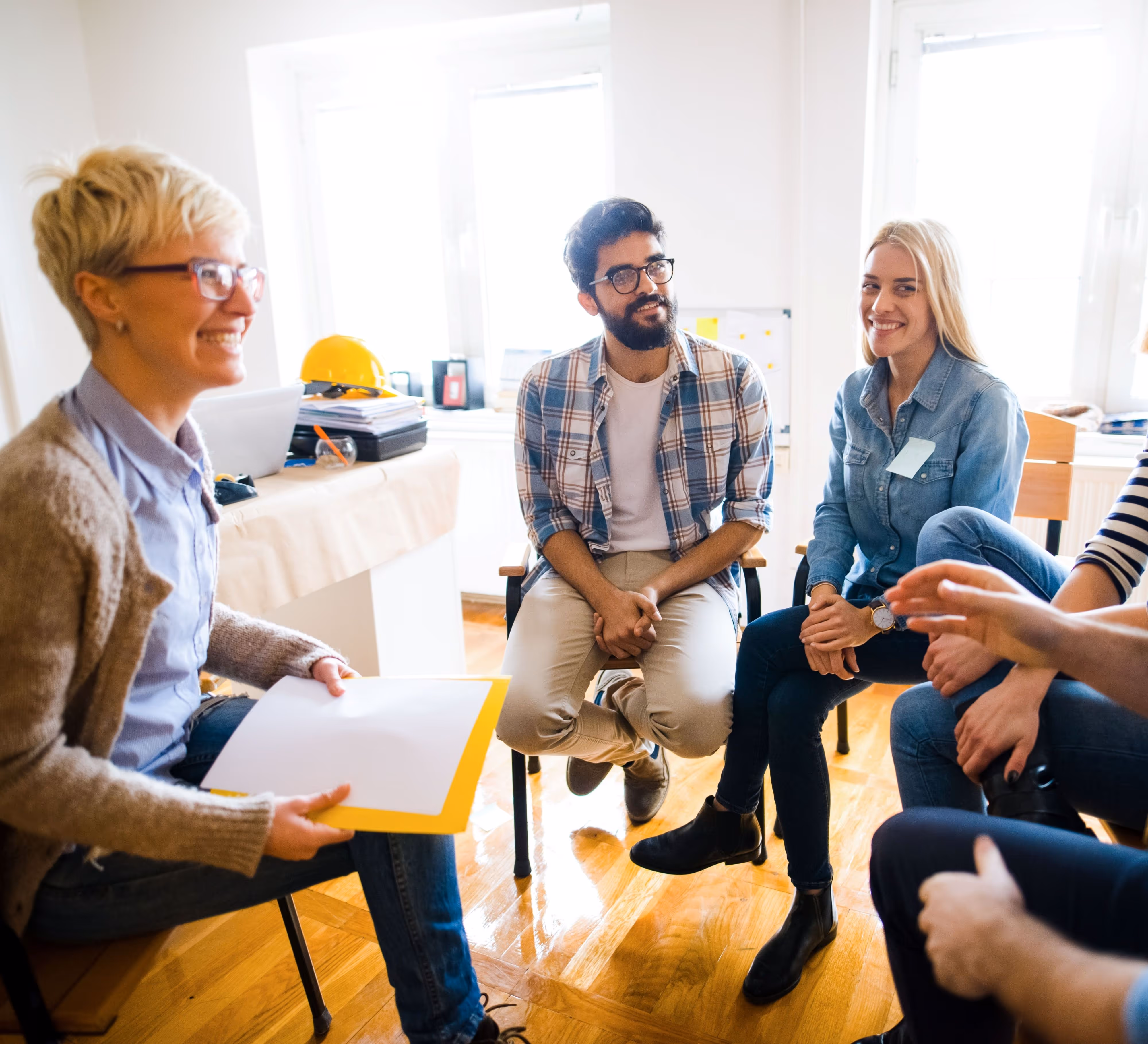 People sitting in a rough circle chatting informally in a light filled room