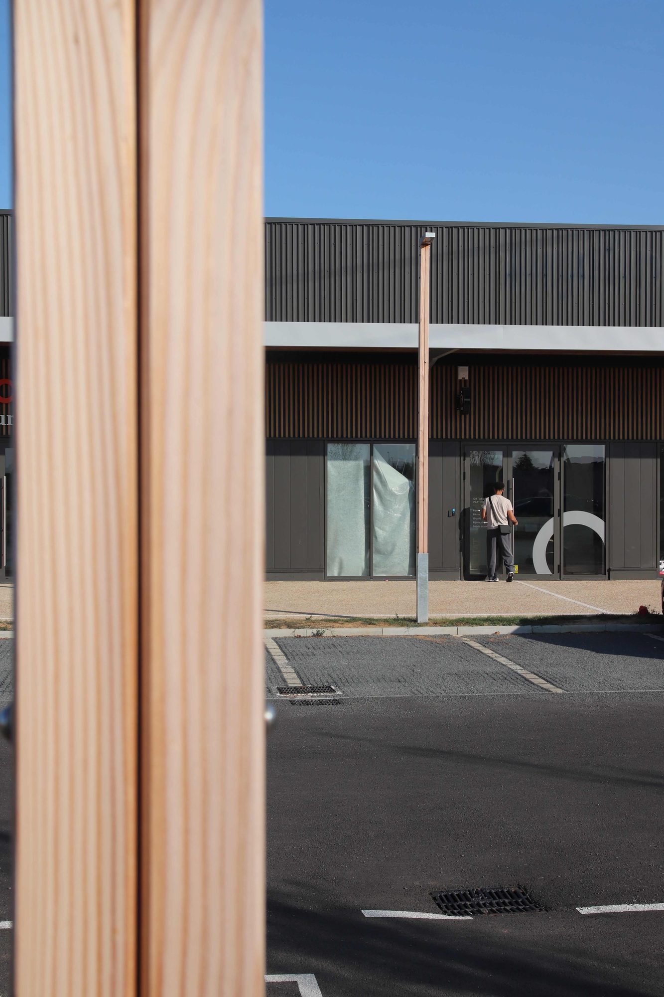 Mât d'éclairage Buho en bois devant une boutique du Triptik Village à Saint-Cyr-sur-Loire