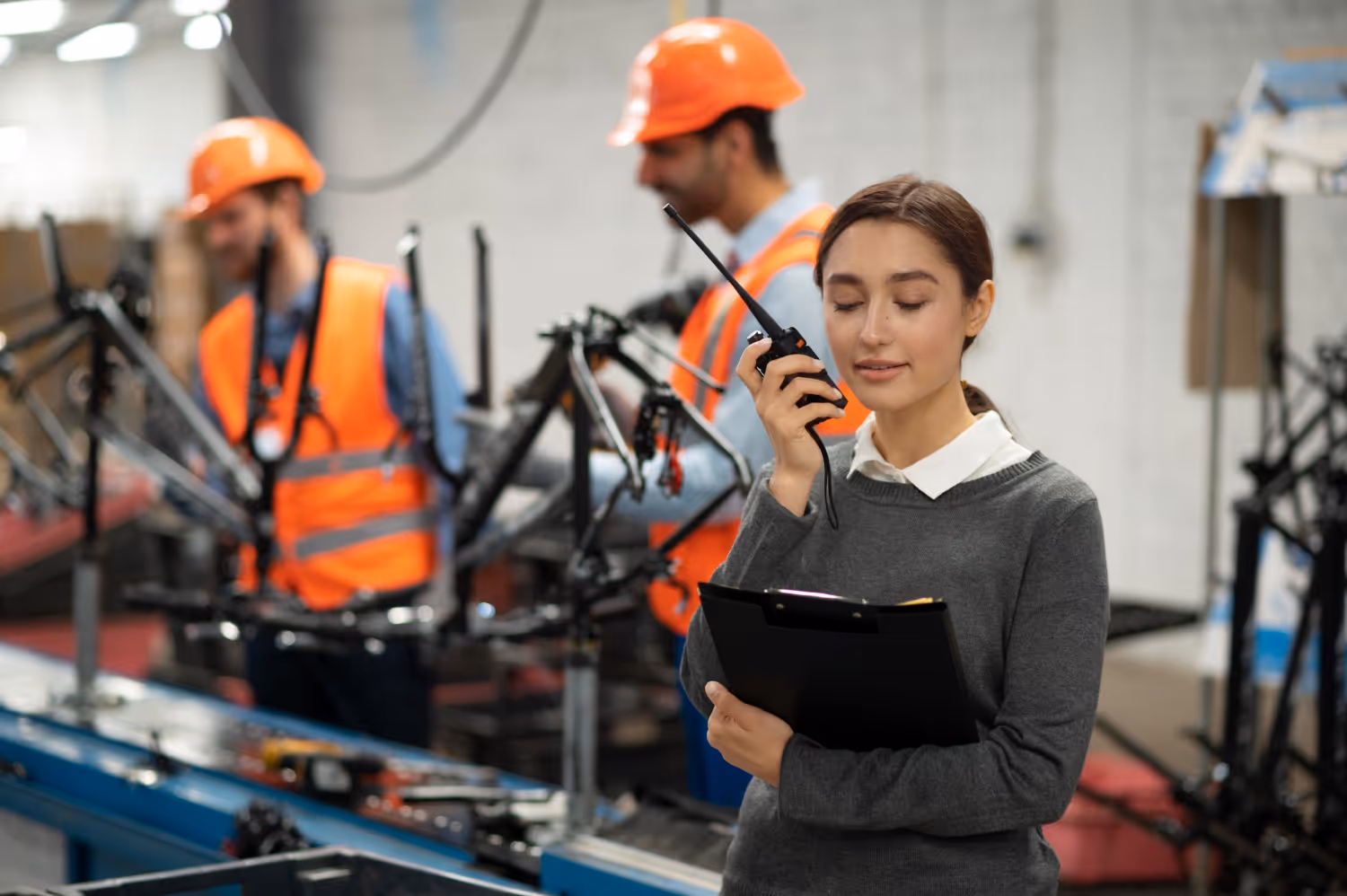 A supervisor with a radio and clipboard on a factory floor