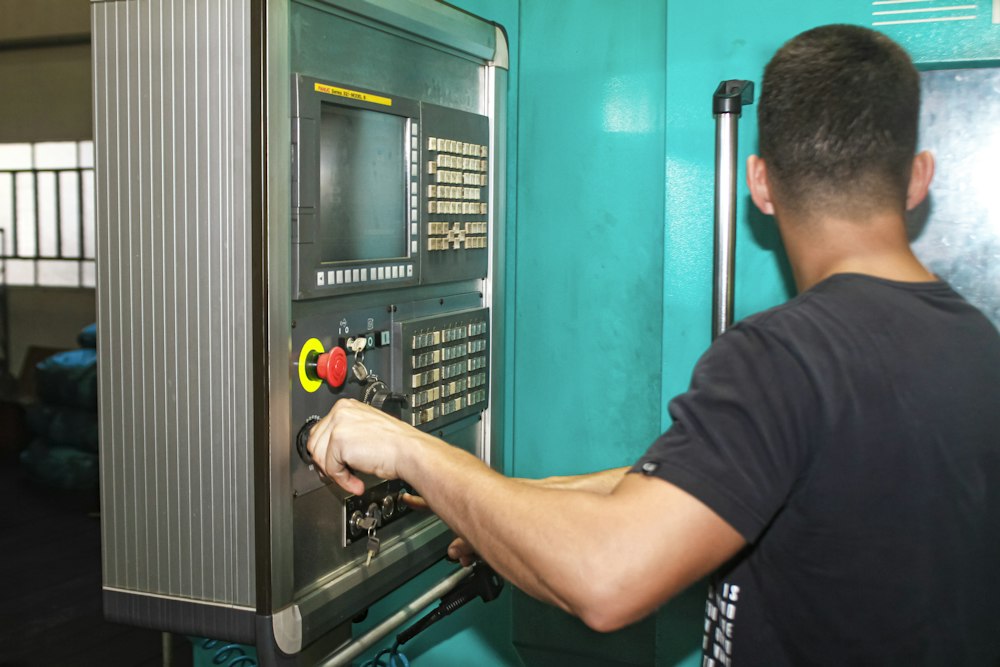 A machinist working the control panel of a CNC machine