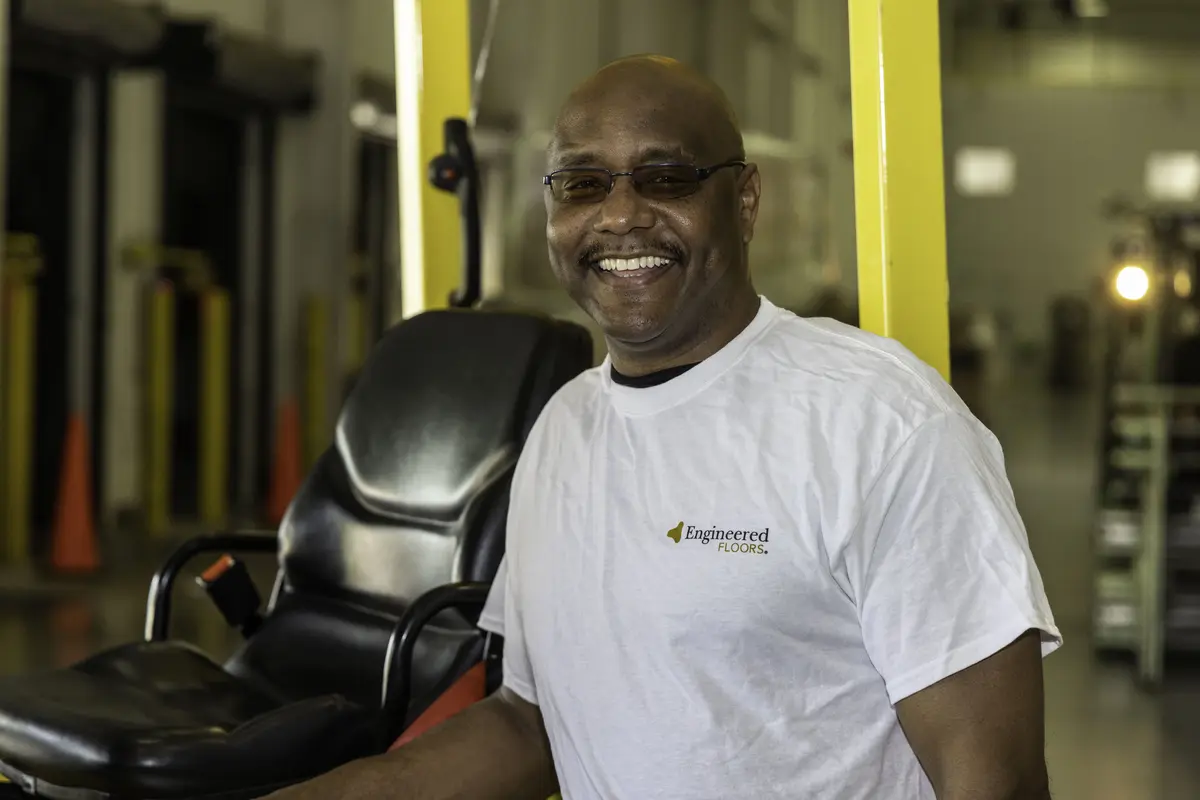 Smiling plant worker beside a forklift