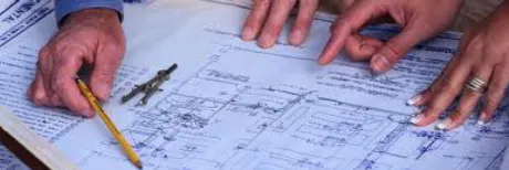 Hands reviewing architectural blueprint with pencil and technical drawing