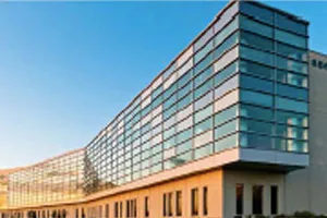 Modern glass and stone office building with blue sky and reflective windows