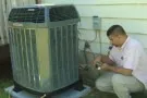 Technician checking and servicing an outdoor air conditioning unit