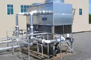 Large industrial cooling tower with metal pipes and support structure outside building