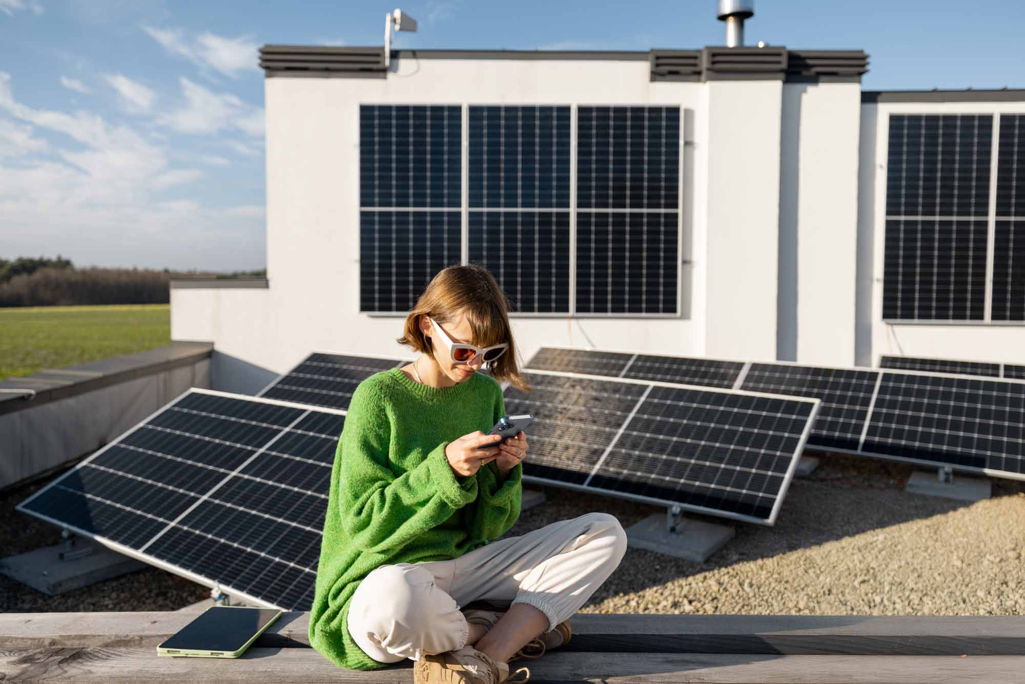 Ein lächelndes Paar sitzt gemeinsam auf einem Sofa vor einem Laptop. Die Frau hält mehrere Rechnungen oder Belege in der Hand, während der Mann mit einem Stift in der Hand auf den Bildschirm zeigt. Beide wirken entspannt und konzentriert – vermutlich bei der Finanzplanung oder Budgetbesprechung.