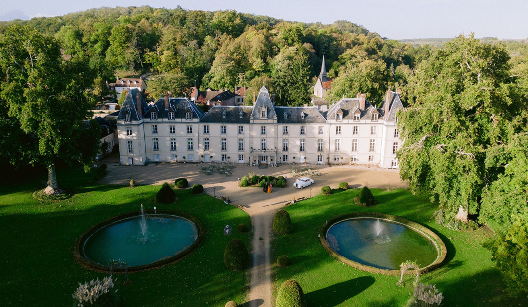 Vue aérienne d'un château avec ses bassins et jardins à la française, domaine idéal pour un mariage d'exception.