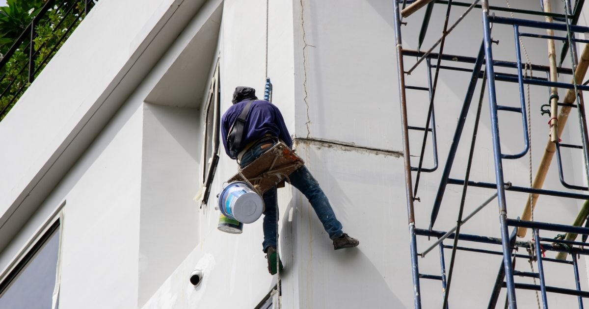 Painter hanging by rope for fixing and painting exterior