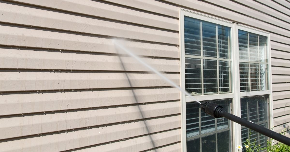 Power washing. House wall vinyl siding cleaning with high pressure water jet